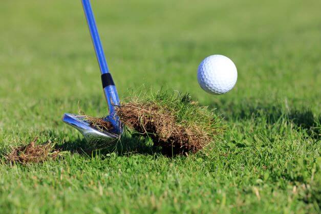 chipping golf ball out of the rough grass