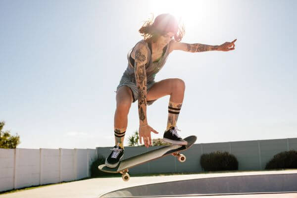 A heavily tattooed lady skateboarding