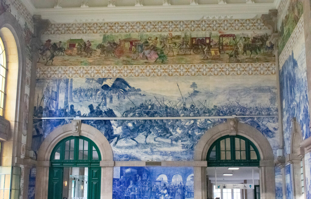 Blue-and-white azulejo tile panels above green doorways inside São Bento station in Porto