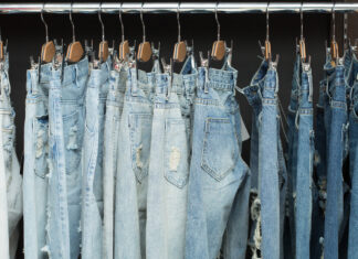 How to buy second-hand jeans that actually fit Blue jeans in different washes hanging from clip hangers on a clothes rail