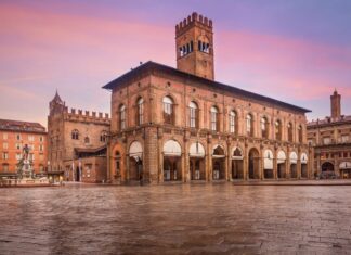 A food-focused weekend in Bologna: a two-night itinerary Historic buildings and the Neptune Fountain beside Piazza Maggiore in Bologna under a pink sky