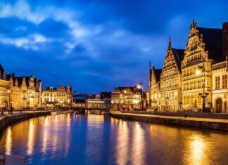 Ghent by train from the UK: how to plan a relaxed two-night city break Illuminated buildings along Graslei and Korenlei reflected in the river in Ghent at dusk