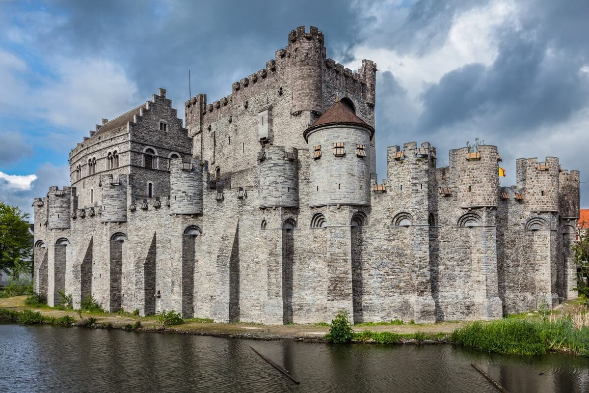 Stone walls and towers of Gravensteen castle beside the water in Ghent