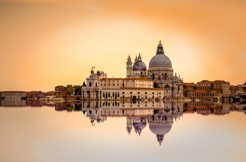 Santa Maria della Salute and Punta della Dogana reflected in the water at sunset in Venice