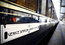Blue and gold Venice Simplon-Orient-Express carriage with its name displayed beside the platform